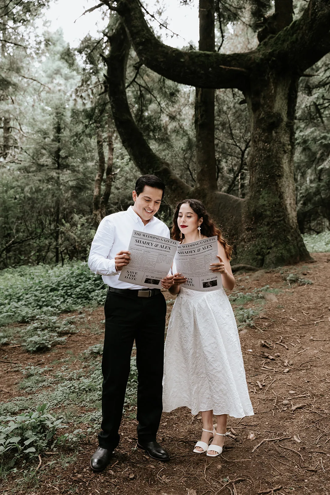Shadey y Alexander leyendo su Save the Date en el bosque